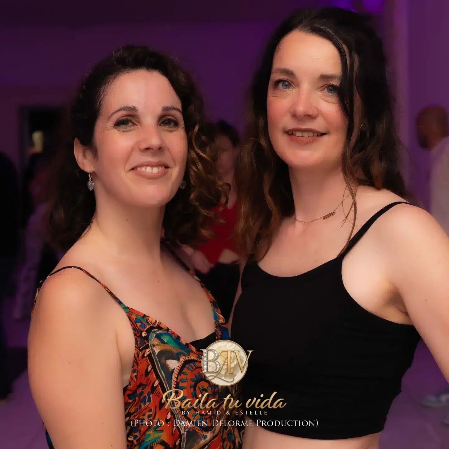 Deux femmes souriantes aux cheveux bouclés, l'une en robe colorée, l'autre en haut noir, à un événement Baila tu vida. Photo Damien Delorme.